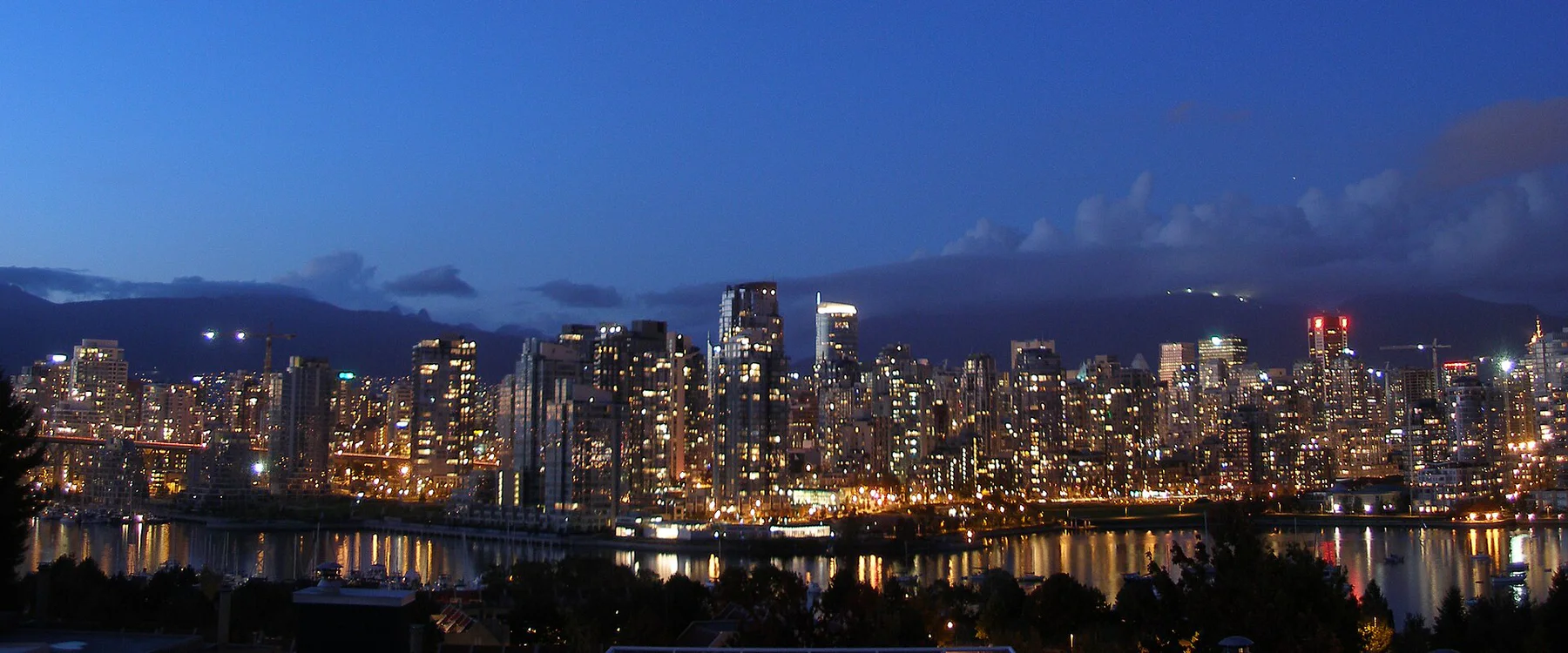 Vancouver skyline illuminated at night with mountains behind it